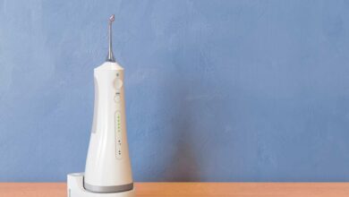 a white color water flosser on a table with blue coloured wall background.