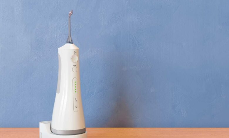 a white color water flosser on a table with blue coloured wall background.