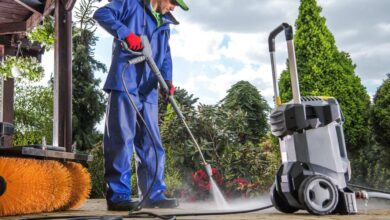 a man in blue washing cloth using pressure washer to clean yard
