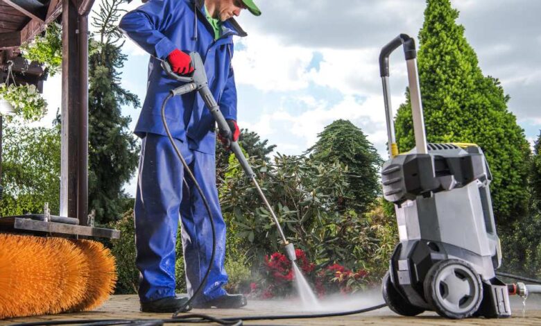 a man in blue washing cloth using pressure washer to clean yard