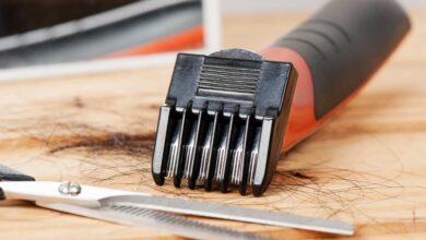 hair clipper and scissor laying on wooden table