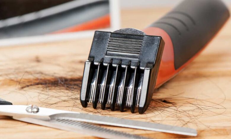hair clipper and scissor laying on wooden table
