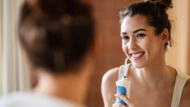 a girl using waterpik water flosser standing in front of mirror.