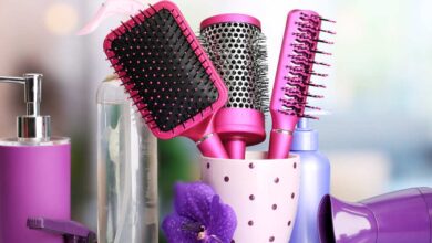 three pink color straightening brushes in a mug and a perfume
