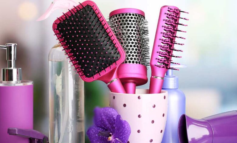 three pink color straightening brushes in a mug and a perfume