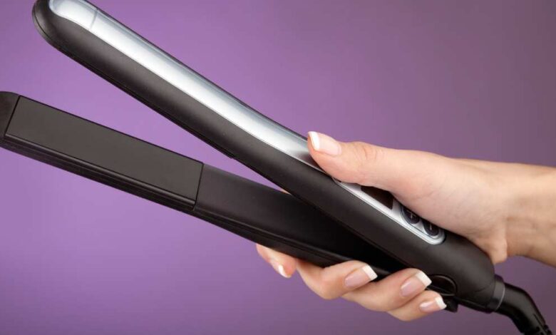 A person holding black color straightener | best hair straightener for men
