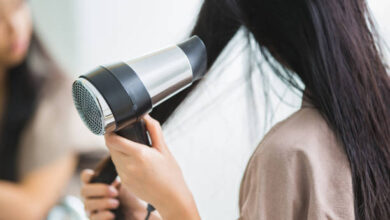 Woman with a 220 volt hair dryer to heat the hair.